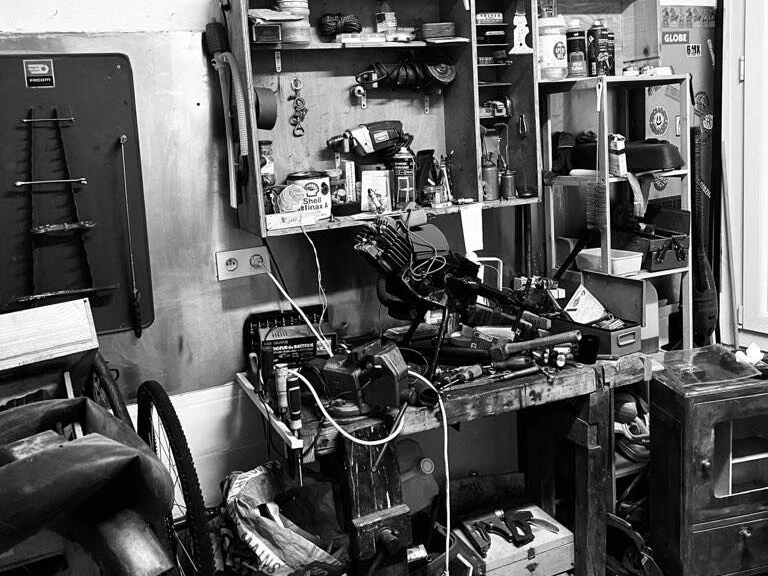 Intérieur de l'atelier "Back to the cyclo", photo en noir et blanc montrant un établi et de nombreux outils